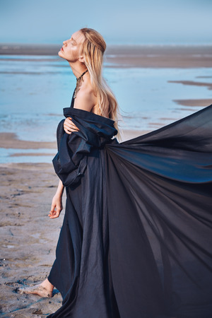 Portrait of a beautiful gothic woman in black dress posing outdoor. Beauty, fashion.の写真素材