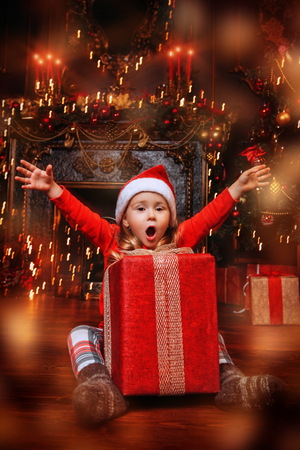 A portrait of a young girl surprised with a big gift box. Decorations for Christmas and New Year. Time for miracles.の写真素材