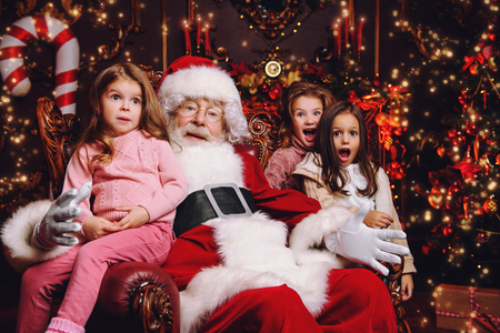 Happy children are sitting at home with Santa Claus. Miracle time. Christmas, New Year.の写真素材
