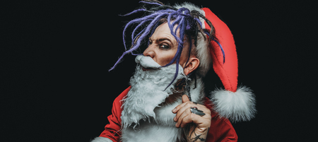 Portrait of a cool punk Santa Claus in luminous glasses with bright dreadlocks over black background.の写真素材