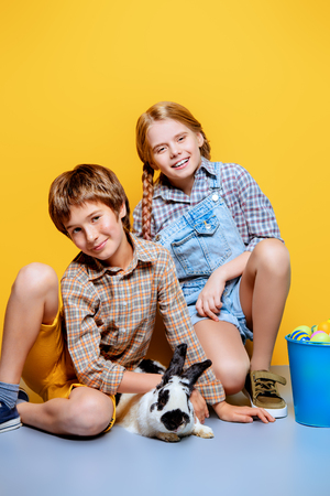 Happy children are posing with Easter attributes on yellow  background. Happy childhood. Easter decorations.の写真素材