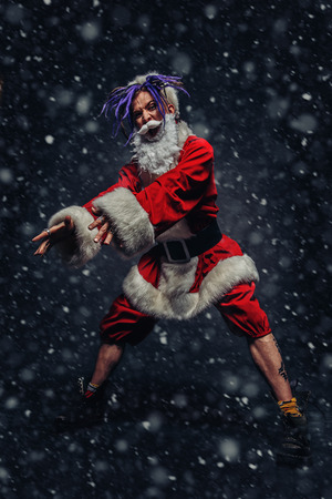 Full length portrait of a cool punk Santa Claus with bright dreadlocks over black background.の写真素材