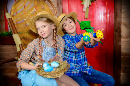 Easter holidays. Happy children are posing on the porch of a village house. Easter decorations.