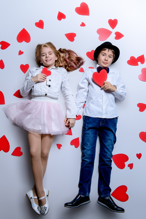 Happy pre-teen boy and girl  are posing surrounded by hearts. Friendship. First love. Valentine's Day.の写真素材
