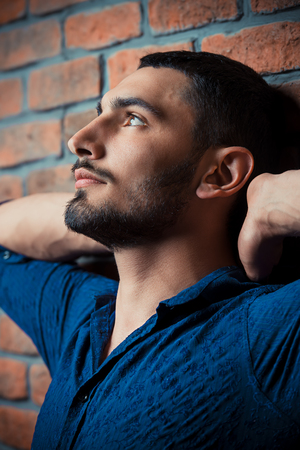 Close-up portrait of a handsome brunet man over brick wall background. Men's beauty, fashion. Men's barbershop, Hairstyle.の写真素材