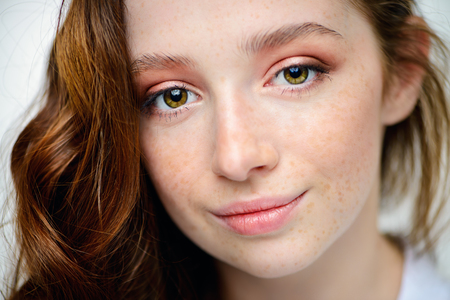 Close-up portrait of a  fifteen-year-old girl with long curly red hair over white background. Beauty, fashion.の写真素材