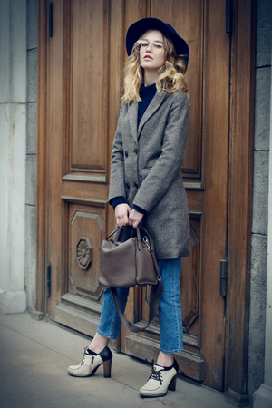 Elegant young woman in a coat and hat is posing on the street. Spring and autumn fashion.の写真素材