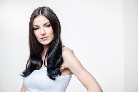 Portrait of a happy young woman with beautiful brunette hair over white background. Long hair concept. Hairstyle, healthy hair. Cosmetics and make-up.の写真素材
