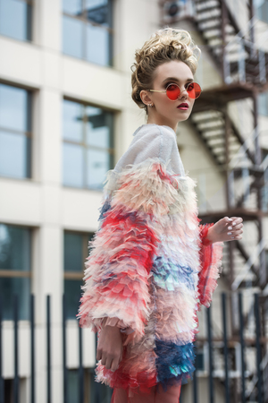 Modern young woman in fluffy dress posing on street outskirts of the city. Beauty, street fashion.の写真素材