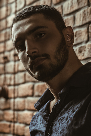 Close-up portrait of a handsome brunet man over brick wall background. Men's beauty, fashion. Men's barbershop, Hairstyle.の写真素材