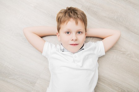 A cute boy is lying on the floor and smiling at camera. Childhood. Kid's fashion.の写真素材