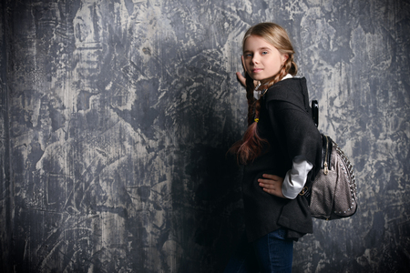 Kid's fashion. A cute modern girl is posing on grunge background at at the studio. Clothes for children.の写真素材