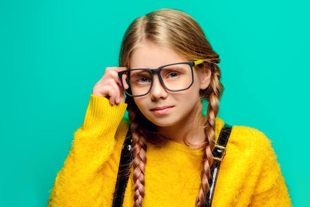 Cute nine year old girl posing in studio in fluffy yellow dress over turquoise background. Children's beauty and fashion.の写真素材
