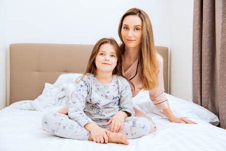 Young woman and her daughter are  funing  with the dishes in the kitchen. Family home shoot. Childhood. Kid's fashion.の写真素材