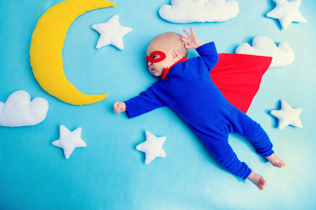 Little baby superhero with red cape flies through the night sky.Children in thematic costumes.の写真素材