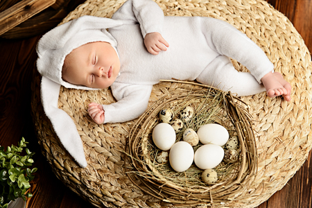 Cute newborn baby lies on a wooden background, dressed in rabbit costume. Easter holiday. Scenery in the rustic style.の写真素材
