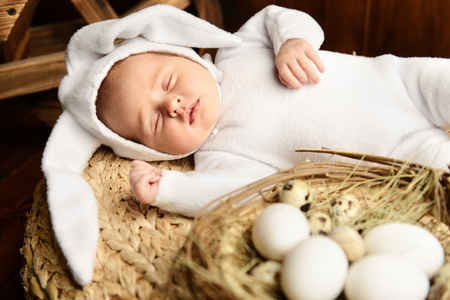 Cute newborn baby lies on a wooden background, dressed in rabbit costume. Easter holiday. Scenery in the rustic style.の写真素材