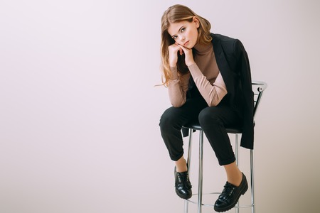 A pretty teenage girl is sitting on a barstool. Beauty, fashion.の写真素材