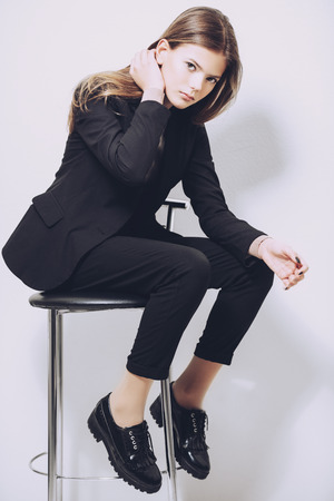 A pretty teenage girl is sitting on a barstool. Beauty, fashion.の写真素材