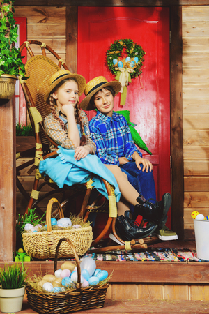 Easter holidays. Happy children are posing on the porch of a village house. Easter decorations.の写真素材