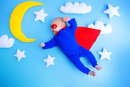 Little baby superhero with red cape flies through the night sky.Children in thematic costumes.の写真素材