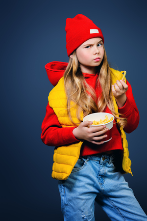 A funny girl in bright casual clothes eating French fries. Beauty, fashion for kids.の写真素材