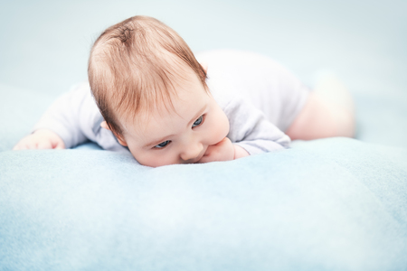A portrait of a beautiful baby crawling in the bed. Family, parenthood. Goods for newborns.の写真素材