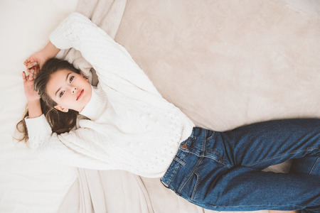 Portrait of a cute girl teenager lying on the bed in the bedroom. Beauty, fashion.の写真素材