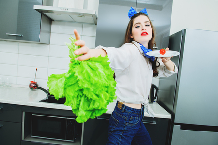 An attractive girl in everyday clothes is cooking in the kitchen. Cooking in the kitchen. Gastronomic concept.の写真素材