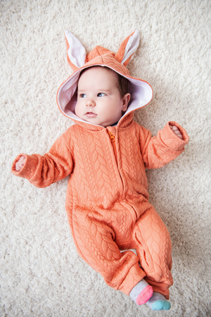 A portrait of a funny baby wearing a jumsuit of a hare. Family, parenthood. Goods for newborns.の写真素材