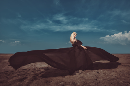 Full length portrait of a beautiful gothic woman in long black dress posing outdoor. Beauty, fashion.の写真素材