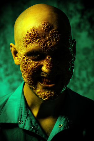 A close up portrait of a sick scientist after a failed experiment in the green light. Desperation, hopelessness. Horror, halloween.の写真素材