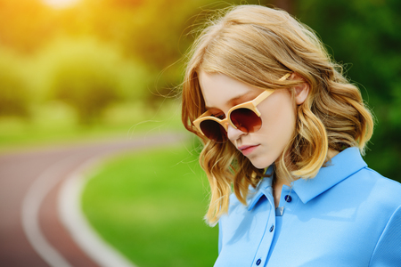 Portrait of a young woman walking in the park. Beautiful young lady in sunglasses. Healthy lifestyle.の写真素材