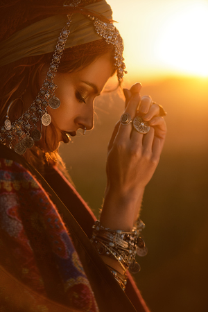 Beautiful fashion model posing in boho style clothes in the rays of the sunset. Outdoor fashion.の写真素材