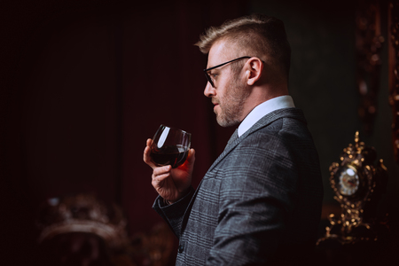 A portrait of a handsome mature man in a formal costume drinking wine. Men's beauty, fashion.の写真素材