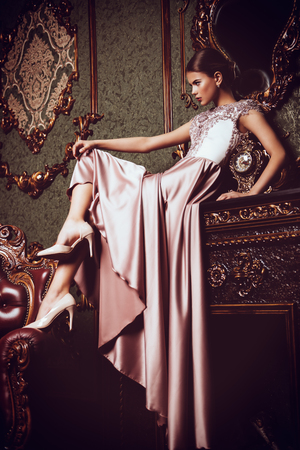 A full length portrait of a mysterious lady in a fluffy long dress posing in the interior. Interior, fashion.の写真素材