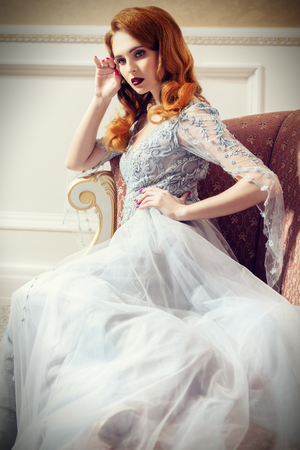 A portrait of a beautiful elegant woman in the wedding dress on the couch. Fashion, wedding dress.の写真素材