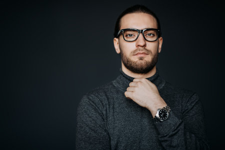A portrait of a handsome man wearing casual clothes and glasses posing in the studio. Men's beauty,...