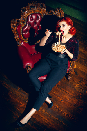 A full length portrait of a beautiful woman posing in the vintage interior and having a meal. Beauty, fashion, interior.の写真素材