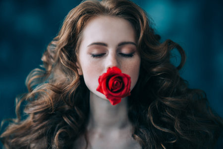 A close up portrait of a lovely mysterious girl with a red rose. Beauty, cosmetics.の写真素材