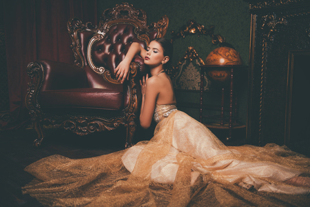 A full length portrait of a mysterious lady in a fluffy long dress posing in the interior. Interior, fashion.の写真素材