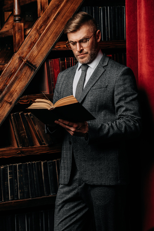 A portrait of a handsome mature man in a formal costume reading a book. Men's beauty, fashion.の写真素材