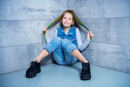 A full length portrait of a young girl posing in the corner in the studio. Beauty, fashion.の写真素材