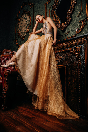 A full length portrait of a mysterious lady in a fluffy long dress posing in the interior. Interior, fashion.の写真素材