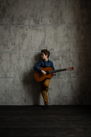 A full length portrait of a young boy posing in the studio with a guitar. Kids, fashion, music, talent.の写真素材