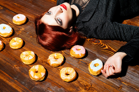 An attractive girl lying next to a lot of donuts on the floor. Beauty, fashion, interior.の写真素材