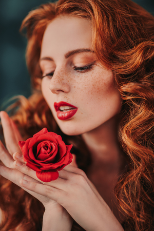 A close up portrait of a lovely mysterious girl with a red rose. Beauty, cosmetics.の写真素材
