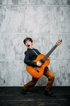A full length portrait of a young boy posing in the studio with a guitar. Kids, fashion, music, talent.の写真素材