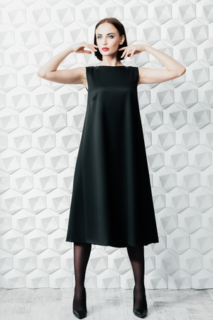 A full length portrait of a beautiful woman wearing a black dress. Fashion, style.の写真素材