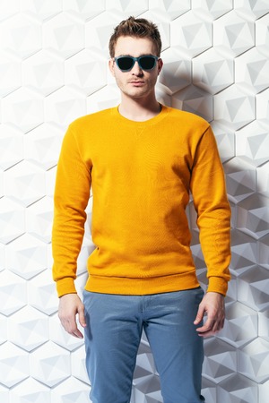 A portrait of a fashionable young man posing with sunglasses in the studio over the white modern background. Casual formal fashion for men, beauty.の写真素材